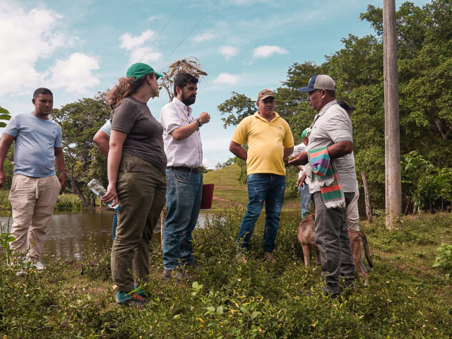 Grupo de personas de la agencia y campesinos reunidos en el campo